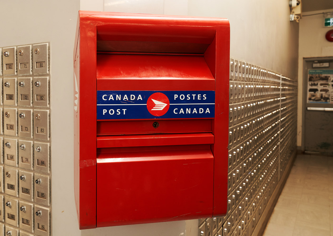Canada Post mailbox in the front with post-office boxes on the wall.