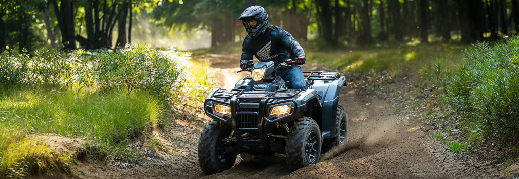 Honda Rubicon rider cruising on a backwoods trail