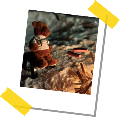 Northy sitting on a log roasting wieners over an open fire